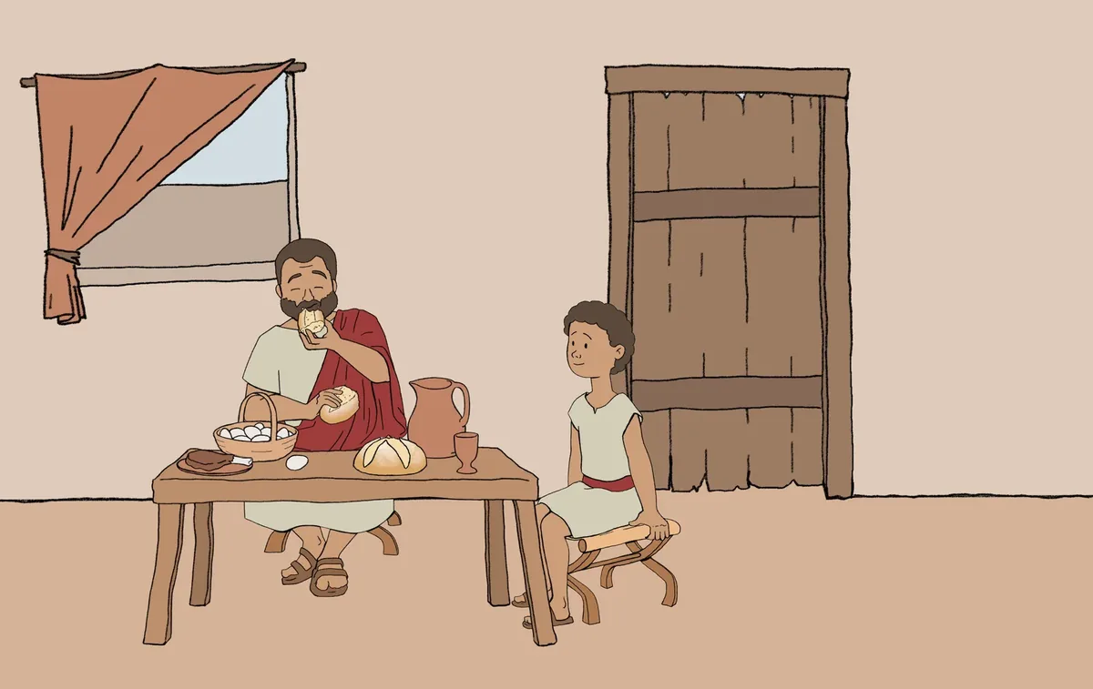 A father sits at the table eating bread while his son sits beside him